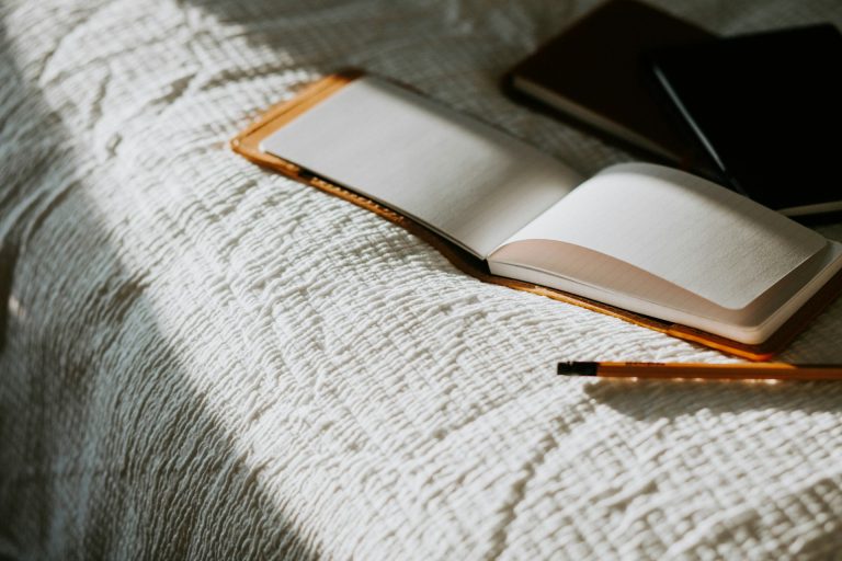 Inicio 20 An open book sitting on top of a bed next to a pencil